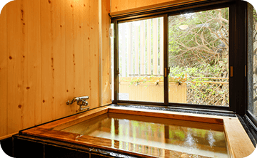 露天風呂付き客室で寛ぐカップルの様子。プライベートな空間で温泉を楽しむ二人時間